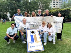 JohnLeonard team posing for group shot around a cornhole board