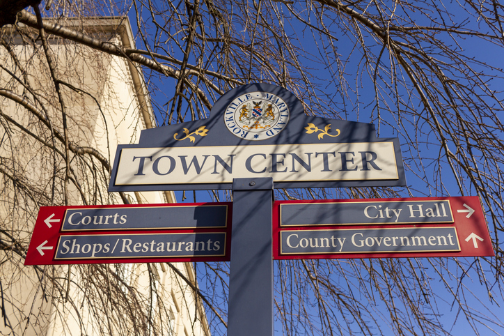 Close up mage of a sign post located in the town center of Rockville, Maryland showing directions of shops, courts and government offices.